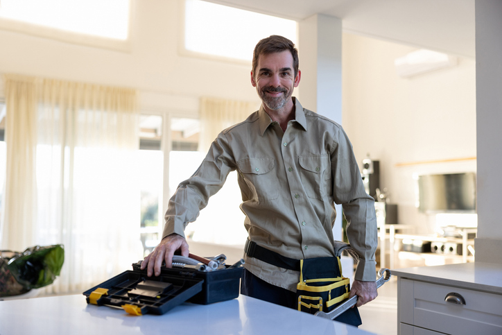 handyman standing in kitchen with tools
